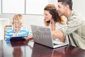 Happy parents showing son how to use tablet pc