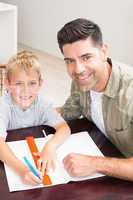 Happy father helping son with homework at table