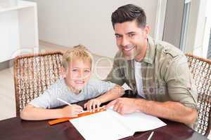Smiling father helping son with homework at table