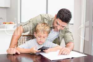 Smiling father helping son with math homework at table