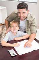 Cheerful father helping son with his math homework at table