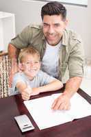 Happy father helping son with his math homework at table