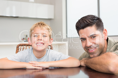 Father and son smiling at camera at the table