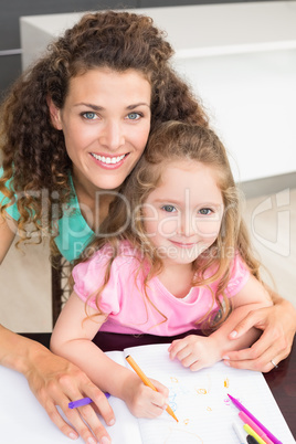 Smiling mother and daughter colouring together at the table
