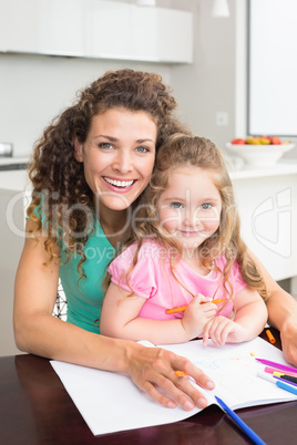 Happy mother and daughter colouring together at the table