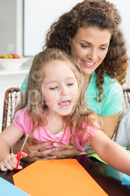 Cheerful little girl doing arts and crafts with mother at the ta