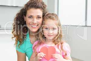 Cute little girl showing paper heart with mother