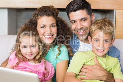 Happy family sitting on sofa with laptop