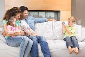 Little boy taking photo of family on the sofa