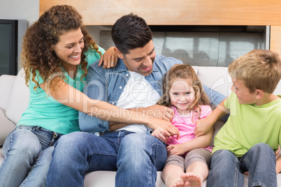 Cute family tickling little girl on the couch