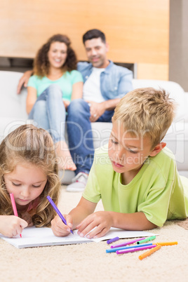Siblings colouring on the rug with parents watching from sofa