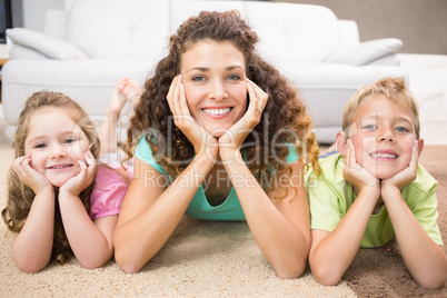 Happy siblings lying on the rug posing with their mother