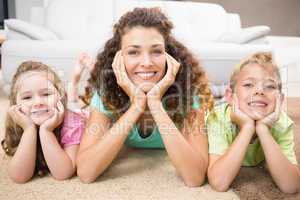 Happy siblings lying on the rug posing with their mother