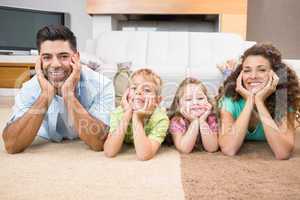 Happy siblings lying on the rug posing with their parents