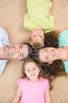 Smiling family lying on the rug in a circle