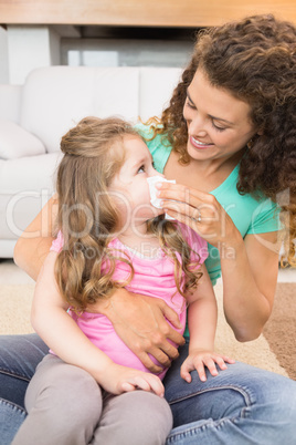 Mother helping her little daughter blow her nose