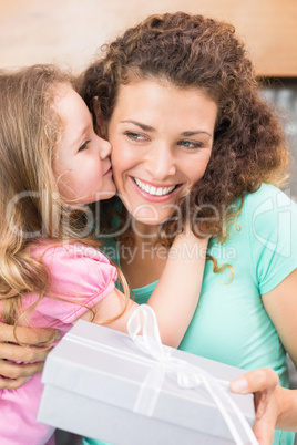 Happy mother getting a kiss and a present from her daughter