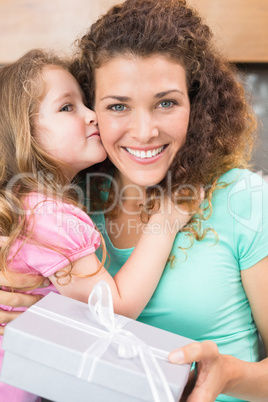 Smiling mother getting a kiss and a present from her daughter