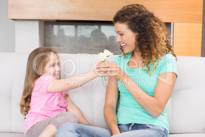 Smiling mother getting little flowers from her daughter