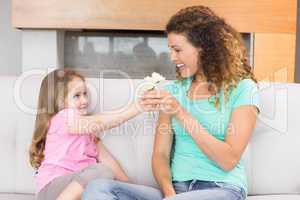Smiling mother getting little flowers from her daughter