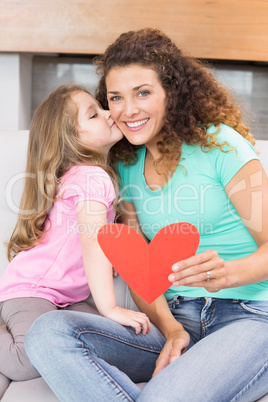 Smiling mother getting a heart card and a kiss from her daughter