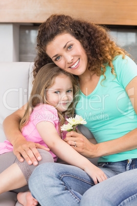 Smiling mother getting little flowers from her cute daughter