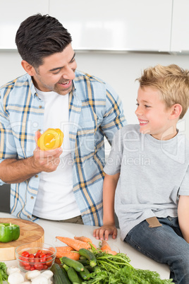 Smiling father showing his son a yellow pepper