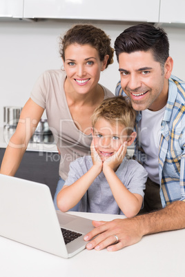 Smiling parents using laptop with their son