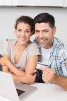 Attractive couple using laptop together to shop online