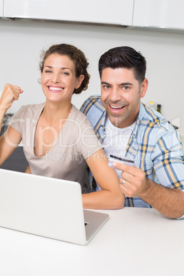 Excited couple using laptop together to shop online
