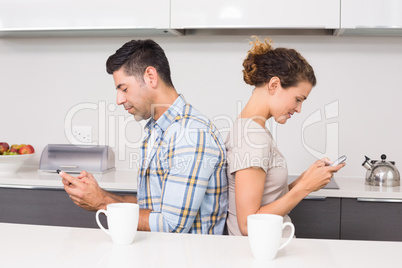 Couple sitting back to back texting