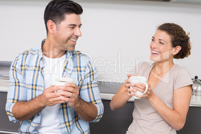 Attractive couple sitting having coffee together and laughing