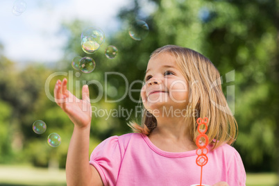 Girl looking at soap bubbles at park