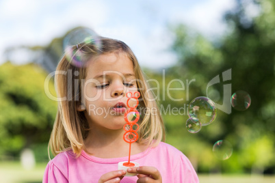 Cute girl blowing soap bubbles at park