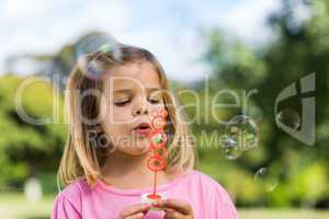 Cute girl blowing soap bubbles at park