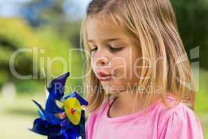 Cute girl blowing pinwheel at park