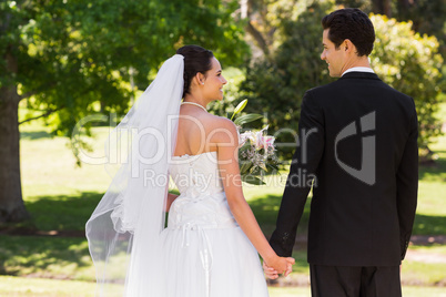 Newlywed couple holding hands and walking in park