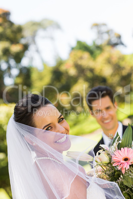 Happy newlywed couple with bouquet in park