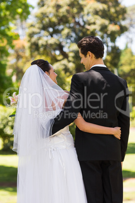 Rear view of newlywed with arms around in park