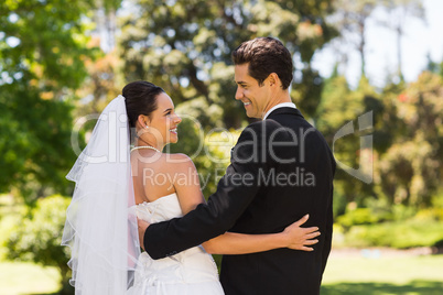 Newlywed couple with arms around in park