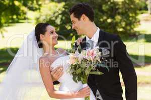 Romantic newlywed couple with bouquet in park