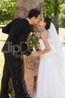 Romantic newlywed couple kissing in park