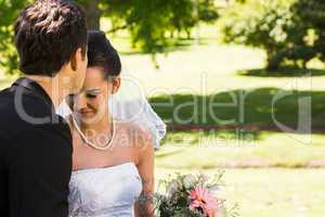 Groom kissing his beautiful bride at park