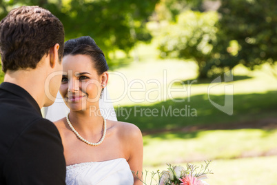 Romantic newlywed couple looking at each other in park