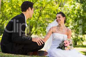 Happy newlywed couple sitting in park