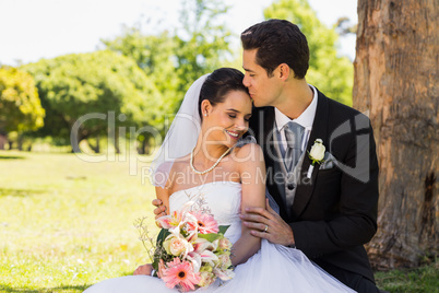 Groom kissing his beautiful bride at park