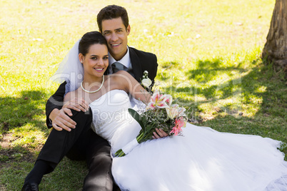 Happy newlywed couple sitting in park