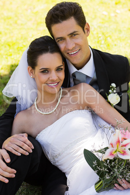 Happy young newlywed couple sitting in park