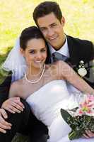 Happy young newlywed couple sitting in park
