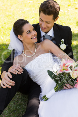 Happy newlywed couple sitting in park